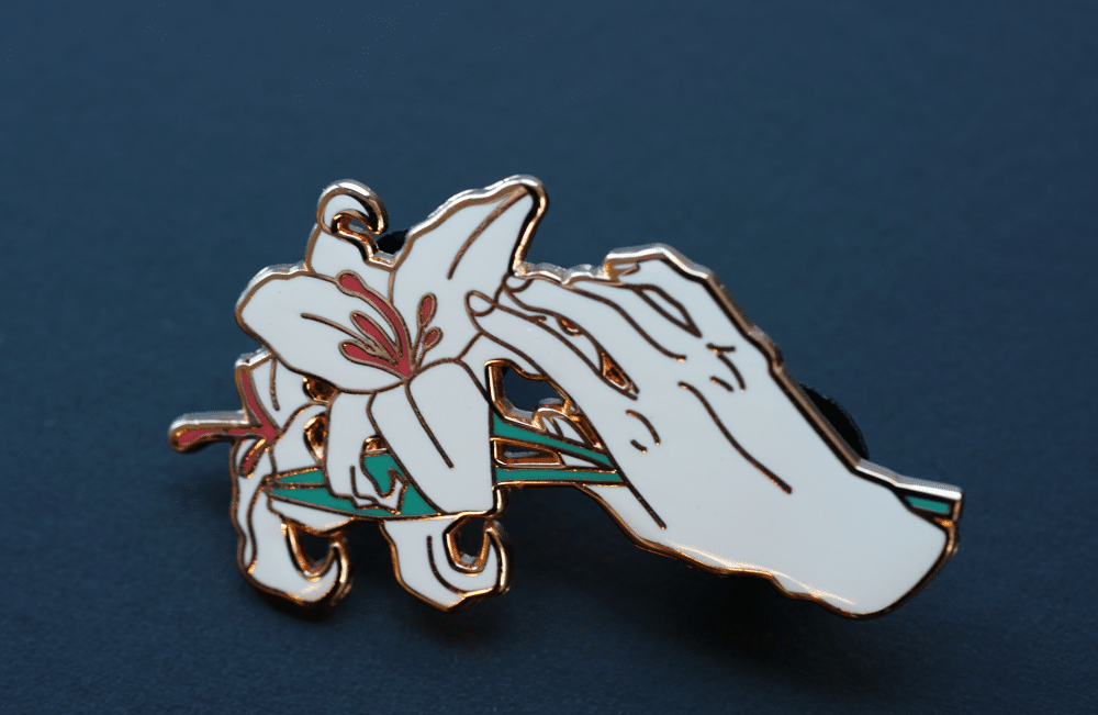 hand holding lily enamel pin